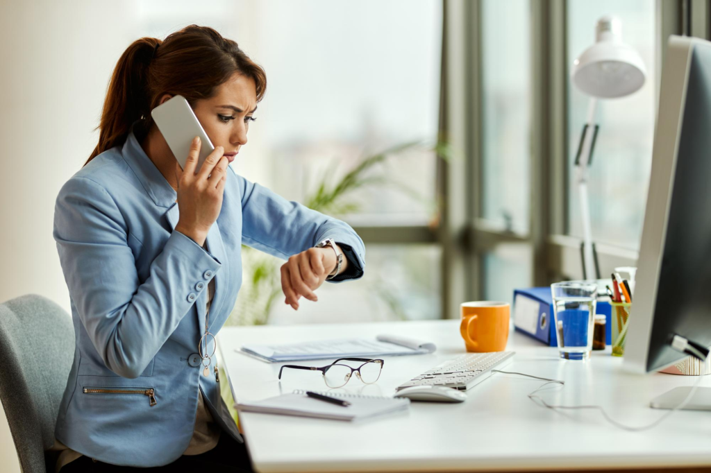 Distraught Australian employee checking her wristwatch during an unreasonable after-hours phone call.